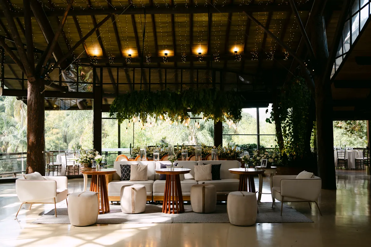 Lounge da recepção sob pergolado com vegetação